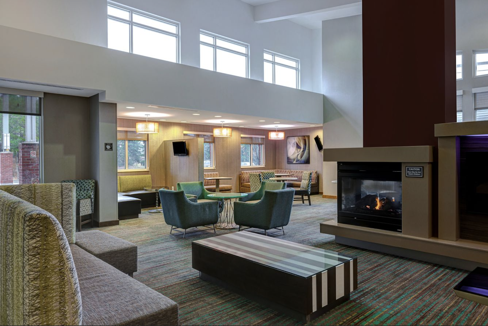 Hotel lobby with soft chairs and a fireplace.